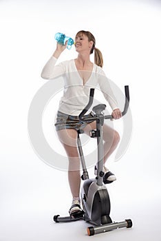 Woman drinking and riding an exercise bike