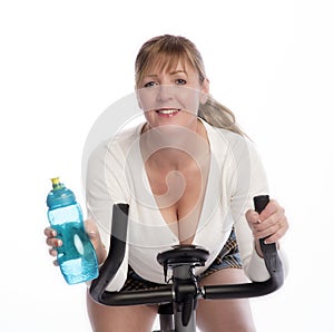 Woman drinking and riding an exercise bike