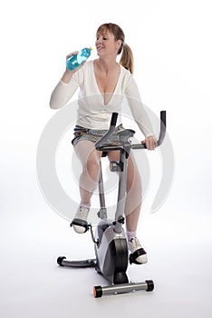 Woman drinking and riding an exercise bike