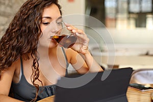 Woman drinking soda and checking tablet in a bar