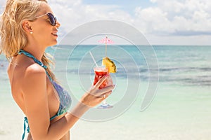 Woman drinking strawberry margarita cocktail on the beach