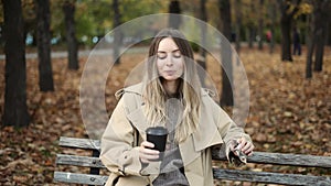 Woman drinking take away coffee and eat chocolate in autumn park