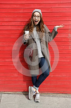 Woman drinking take away coffee and holding copyspace on palm