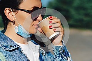 Woman drinking take away coffee. Profile of pretty girl wearing sunglasses