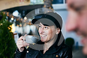 A woman is drinking tea in a cafe at a meeting with friends.