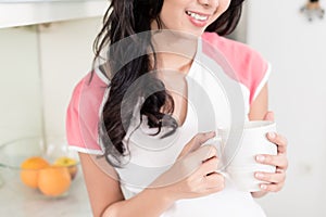 Woman drinking tea or coffee in her Asian kitchen