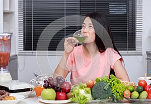 Woman drinking vegetable juice in kitchen