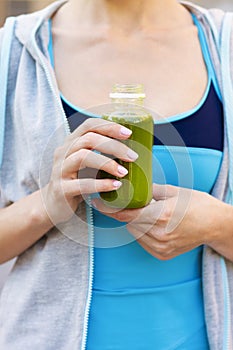 Woman drinking vegetable smoothie after fitness running workout
