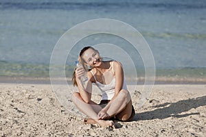 Woman drinking water from a bottle on the beach portrait