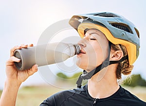 Woman drinking water, bottle and cycling with exercise outdoor, helmet for safety and health with hydration. Athlete