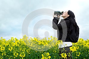 Woman drinking from water bottle in field