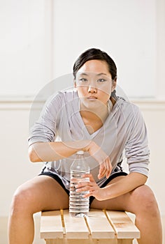 Woman drinking water from bottle in health club
