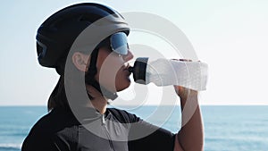 Woman drinking water from bottle after intense cycling training. Professional cyclist in cycling apparel drinks water to stay hydr