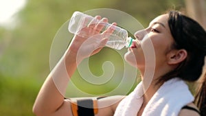 Woman drinking water from bottle after working out, outdoor sport brunette girl drink clear mineral water after training
