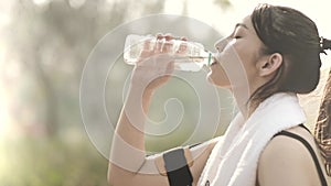 Woman drinking water from bottle after working out, outdoor sport brunette girl drink clear mineral water after training