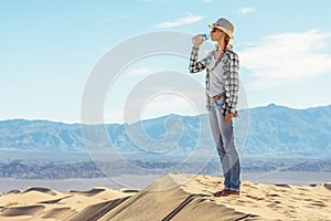 Woman drinking water in desert. Active girl quenches thirst in Death Valley, California, USA