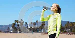 Woman drinking water after doing sports outdoors