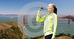 Woman drinking water after doing sports outdoors