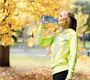 Woman drinking water after doing sports outdoors