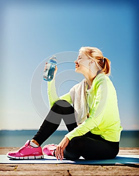 Woman drinking water after doing sports outdoors