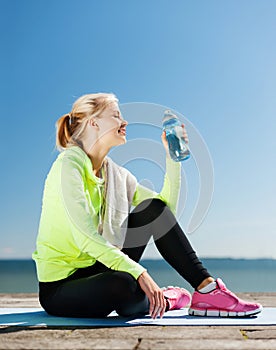 Woman drinking water after doing sports outdoors