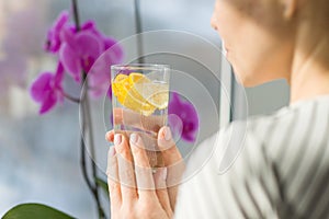 Woman drinking water with fresh organic lemon.