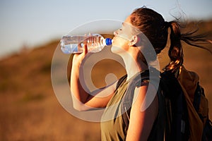 Woman, drinking water and hiking outdoor for fitness or travel, thirst and hydration with exploring nature. Backpacking