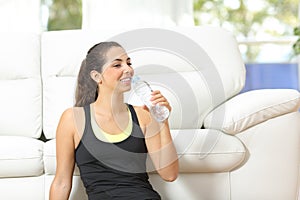 Woman drinking water at home after sport