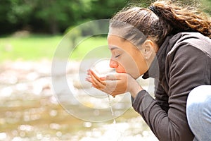 Woman drinking water from river