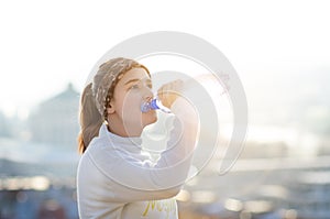 Woman drinking water during a running. Cold weather. Jogging woman in a city during a winter. Sunny day. Drinking mode.