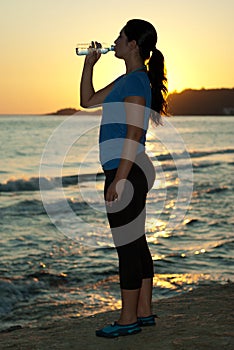 Woman drinking water by sunset