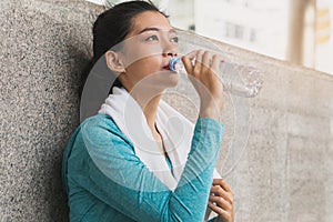 woman drinking water to rehydrate to avoid heat stroke after running outdoors in the summer