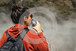 Woman drinking water while touring in hot pools at Kuirau Park. Rotorua, New Zealand