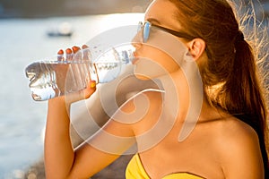 Woman drinking water from transparent bottle on