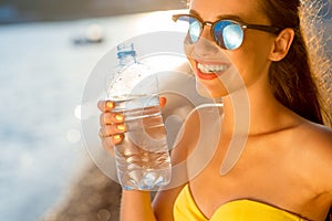 Woman drinking water from transparent bottle on