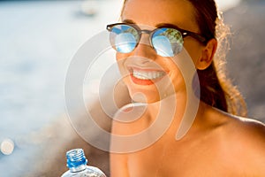 Woman drinking water from transparent bottle on