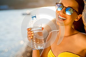 Woman drinking water from transparent bottle on