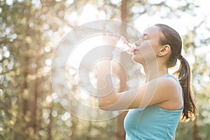 Woman drinking water after work out exercising on sunset evening