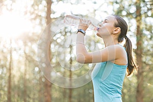 Woman drinking water after work out exercising on sunset evening