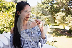 Woman drinking white wine while standing in balcony at restaurant