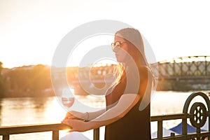 Woman drinking a wine in the city during a sunset. Glass of red wine. Concept of free time in the city and drinking alcohol.