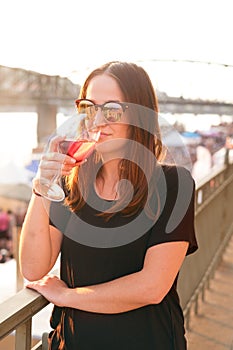 Woman drinking a wine in the city during a sunset. Glass of red wine. Concept of free time in the city and drinking alcohol.