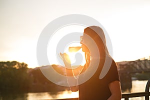 Woman drinking a wine in the city during a sunset. Glass of red wine. Concept of free time in the city and drinking alcohol.