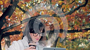 Woman drinkink coffee and working with her notebook outside