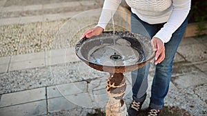 Woman drinks clean fresh water from a street water fountain while feeling the thirst