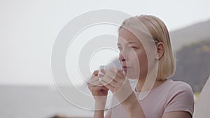 A woman drinks coffee on the balcony of a hotel with a beautiful view of the sea.