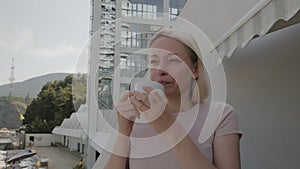 A woman drinks coffee on the balcony of a hotel with a beautiful view of the sea.