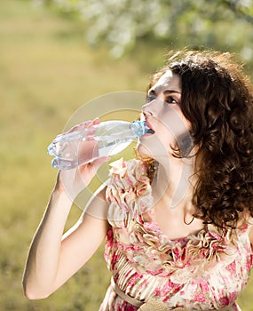 Woman drinks cold water in spring garden