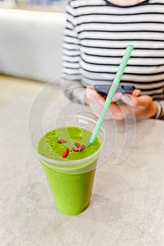 Woman drinks green vegetarian and vegan smoothies with goji berries