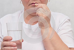 A woman drinks a hormonal pill for treating the thyroid gland, eliminating nodules and normalizing hormones, treatment, close-up